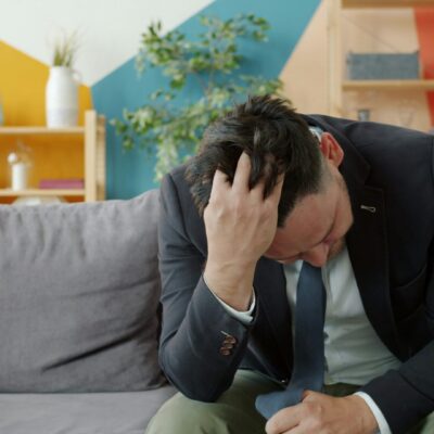 man holding his head while on couch picture