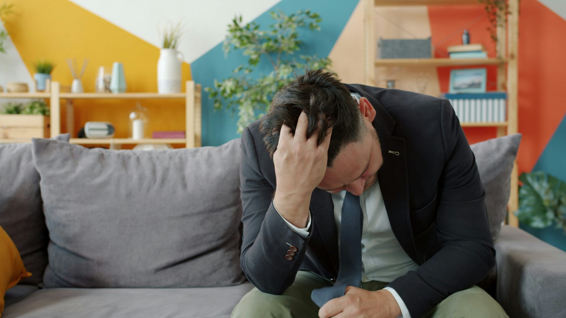 man holding his head while on couch picture